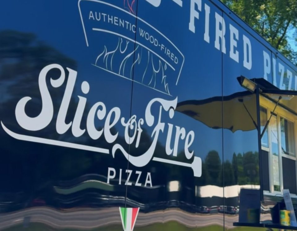 Logo of Slice of Fire Pizza on a glass window.