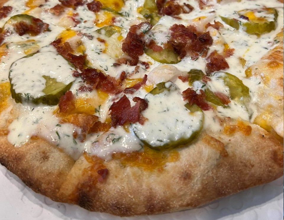 Close-up of a pizza with cheese, jalapeños, and bacon bits.